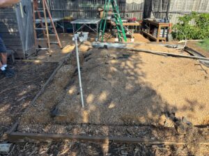 This picture shows where the old greenhouse used to be standing and now in its place is just a granite base and a few pipes. You can see the garden workbench area in the background.